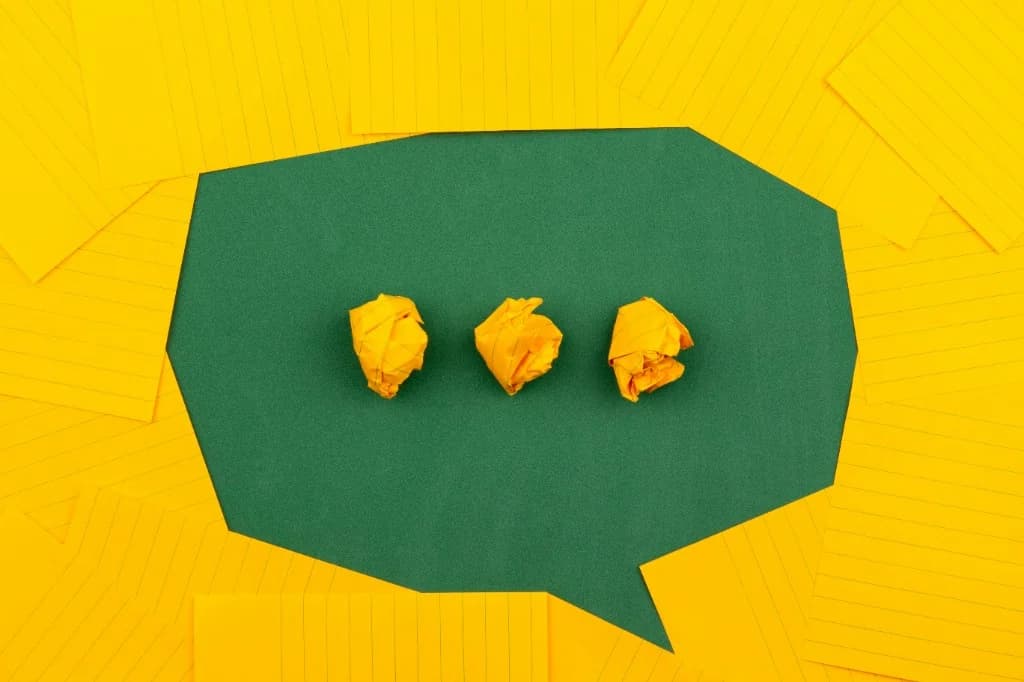 Post-it jaunes formant une bulle de dialogue sur fond vert, avec trois boules de papier : image de la communication et du temps de réponse.