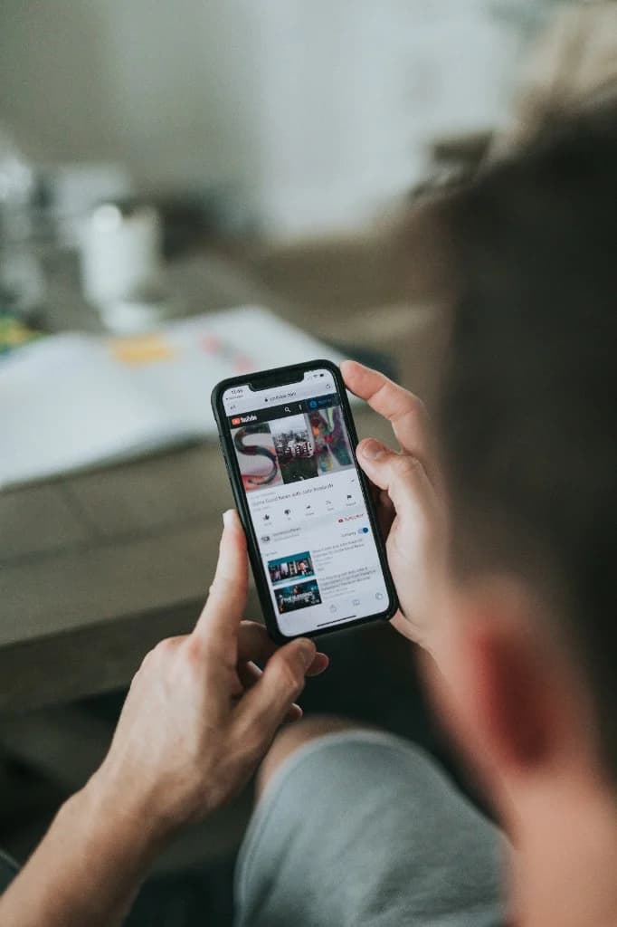 Person sitting with a smartphone, screen showing online video — what in-person connection goes beyond.