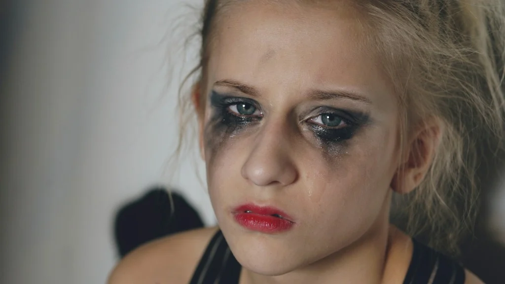 Close-up portrait of a young woman crying with smudged makeup — raw emotion after disappointment.