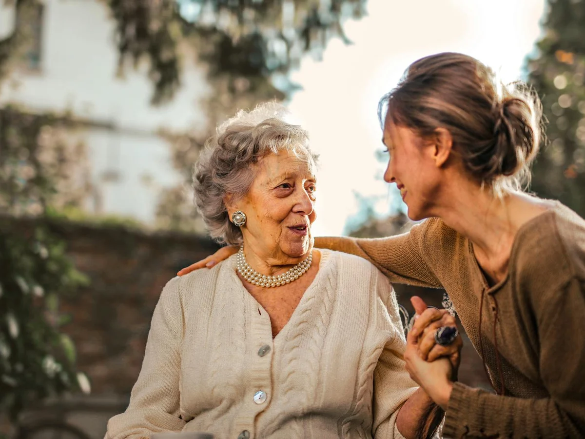 Two generations smiling outdoors in a sunny garden